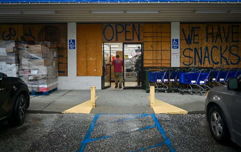 A person walks into a store boarded up with wood as preparations are made for the arrival of Hurricane Helene, in Steinhatchee, Florida, on September 25, 2024