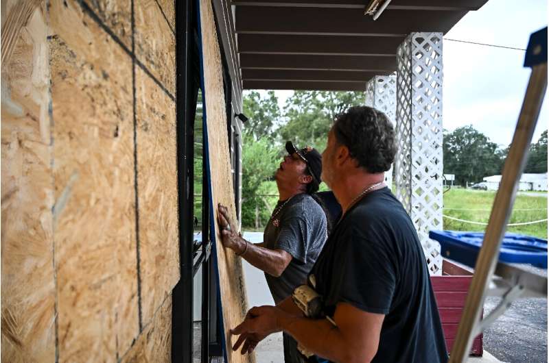 Rick Chouinard (R) and Donald Tointigh install boards over windows of their shop ahead of the arrival of Hurricane Helene in Crawfordville, Florida on September 25, 2024. Rick Chouinard (R) and Donald Tointigh install boards over windows of their shop ahead of the arrival of Hurricane Helene in Crawfordville, Florida on September 25, 2024